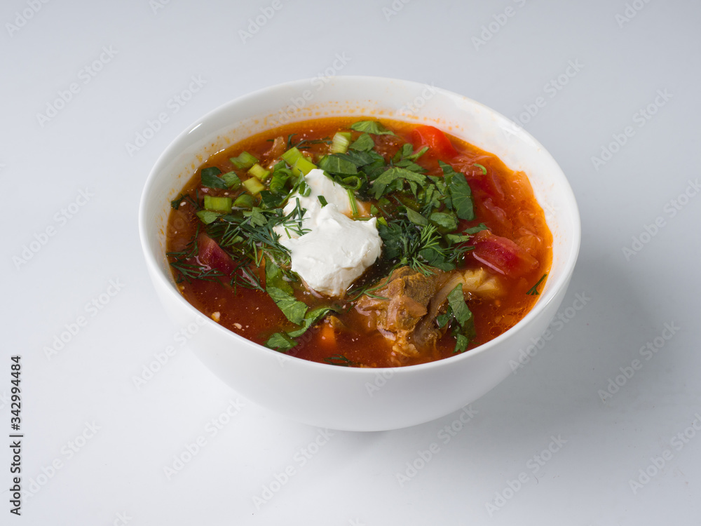 Borsch with sour cream in a white bowl on a white background. Side view