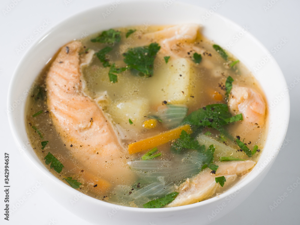 Fish soup in a white bowl. Salmon with potatoes and herbs. Side view Fish soup in a white bowl. Salmon with potatoes and herbs. Side view