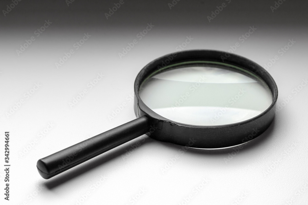 A black magnifier lies on a white windowsill. A black magnifier lies on a white windowsill.