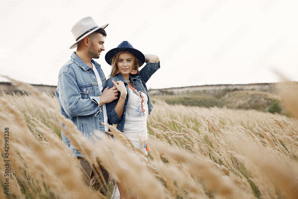 Loving couple in a wheat field. Beautiful blonde in a blue hat.