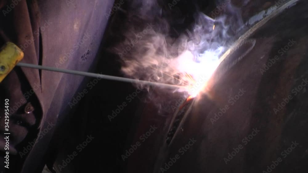 welder is repairing the defective area of the weld inside the parts of chemical apparatus. Blue smoke and yellow-red sparks fly from the electrode in all sides.
welder is repairing the defective area of the weld inside the parts of chemical apparatus. Blue smoke and yellow-red sparks fly from the electrode in all sides.