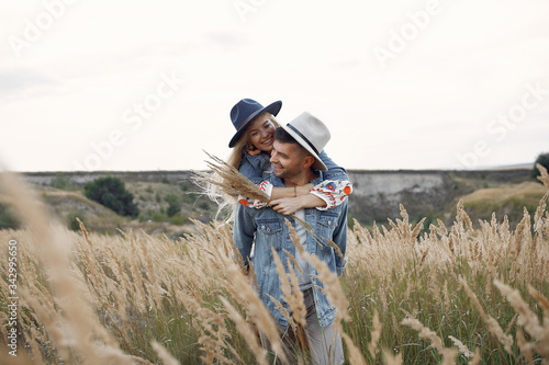 Loving couple in a wheat field. Beautiful blonde in a blue hat.