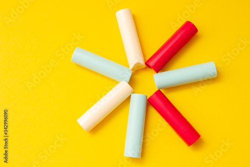 Bright multi-colored cosmetic lipstick on a yellow background in the shape of the sun