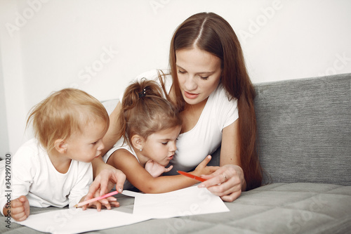 Cute family in a room. Lady in a white shirt. Mother with cute children