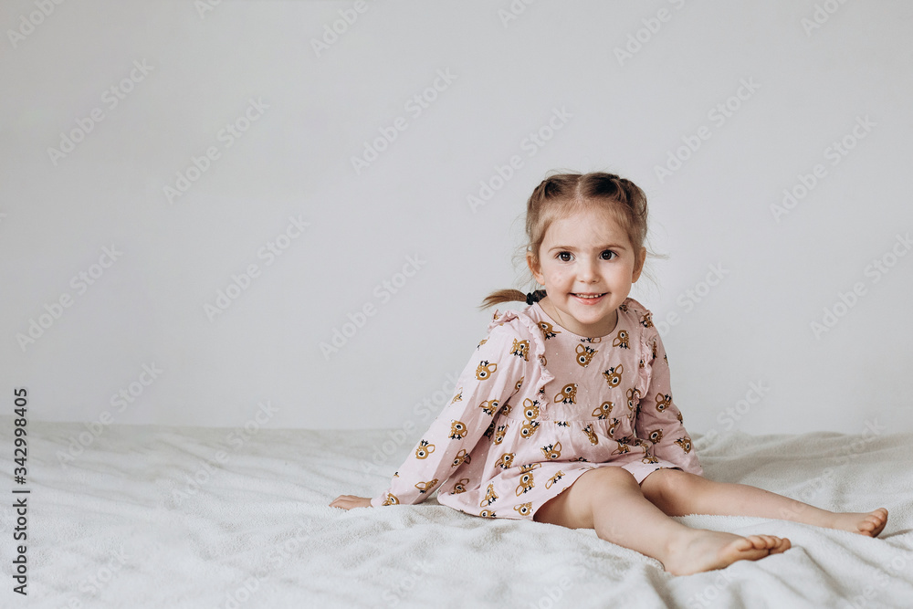 Happy three year old girl sitting on a white background Happy three year old girl sitting on a white background