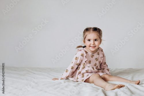 Happy three year old girl sitting on a white background