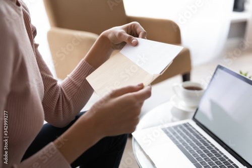 Close up side view young woman holding craft paper envelope correspondence, getting blank paper sheet invitation. Worrying student received university admission notification with postal letter. © fizkes
