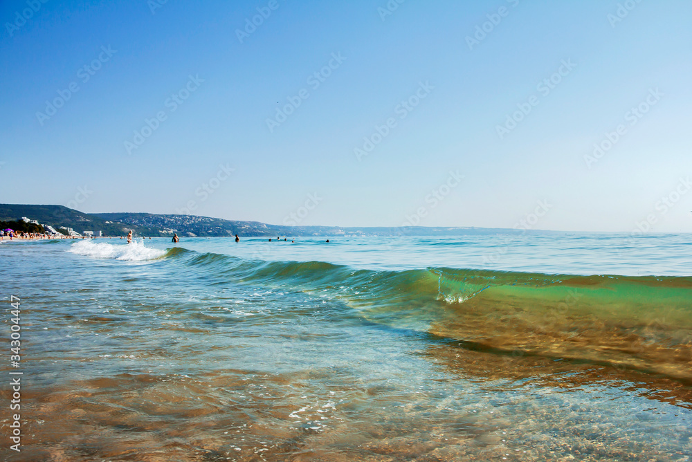 Oncoming sea wave on a sandy beach in summer on a sunny day. Bulgarian coast of the Black Sea.