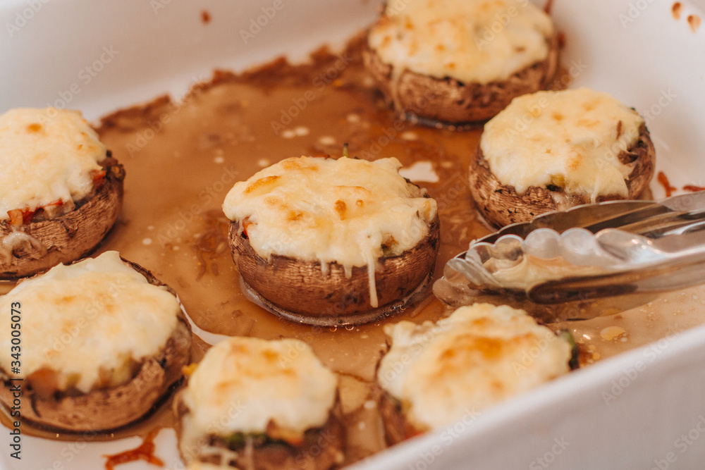 Freshly baked champignons with cheese and vegetables on a white plate Freshly baked champignons with cheese and vegetables on a white plate