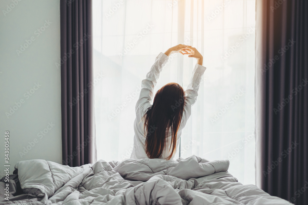 © joyfotoliakid - Asian woman wake up on bed stretching feeling happy and fresh enjoying in the morning