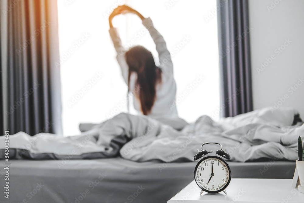 Asian woman wake up on bed stretching feeling happy and fresh enjoying in the morning - obrazy, fototapety, plakaty 