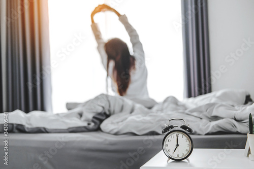 Asian woman wake up on bed stretching feeling happy and fresh enjoying in the morning photo