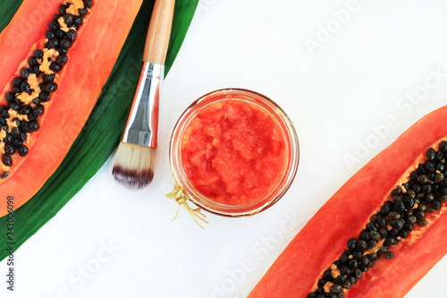 Mashed papaya facial mask, fruit pieces top view with glass jar of eco spa skin care product