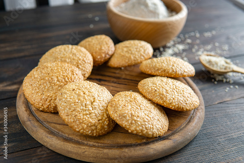 Freshly baked homemade sesame seed cookies on wooden board, rustic table. Healthy, tasty snack, honey seed bar, round form biscuits. Organic dessert, country style.