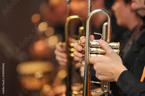 trumpet held by trumpeter waiting his turn, with other trumpets out of focus behind