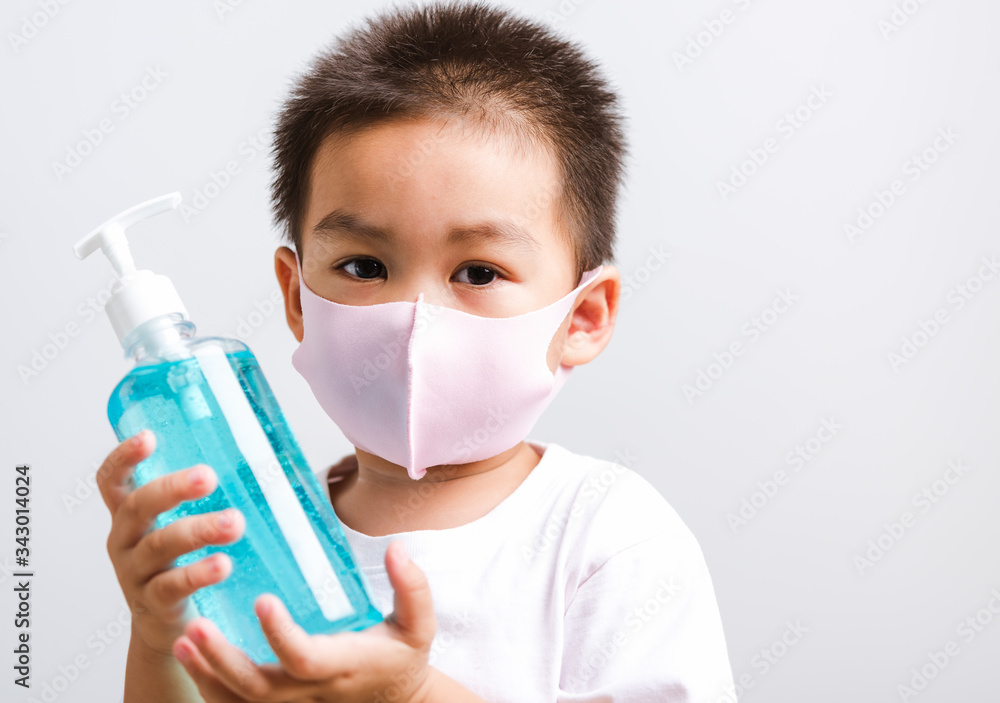 Closeup portrait Asian little child boy holding show bottle pump dispenser sanitizer alcohol gel hand wash cleaning, COVID-19 or coronavirus protection concept, isolated on white background