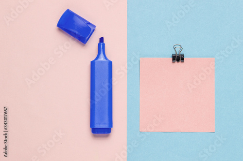 Stationery office supplies. Paper clip, felt-tip pen, memo piece of paper on pink blue pastel the background