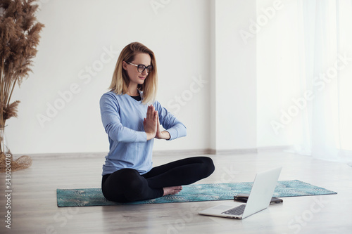 women doing yoga at the home online (sports exercises), have fun, spend a good time . the concept of a healthy lifestyle. quarantined sports life and online studying