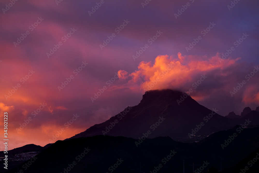 Coloured purple violet sunset at the muntain with white clouds above - beautiful mounts landscape with amazing colors - concept of nature and outdoors