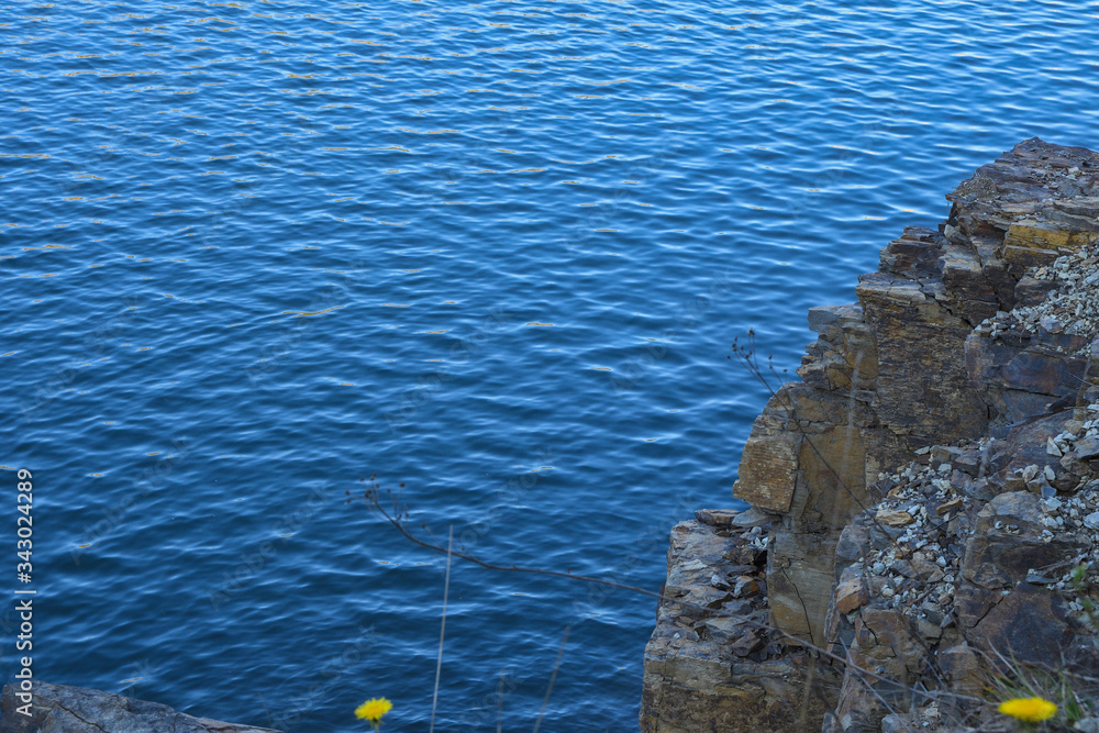 Stone rocks near water, on the background of lake, river, sea, ocean. Blue clear water. Artificial reservoirs Stone rocks near water, on the background of lake, river, sea, ocean. Blue clear water. Artificial reservoirs