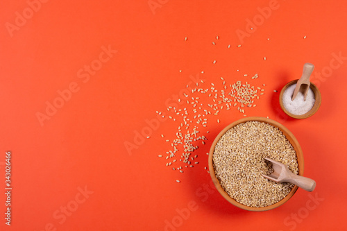 Pearl barley in a plate on a orange background.