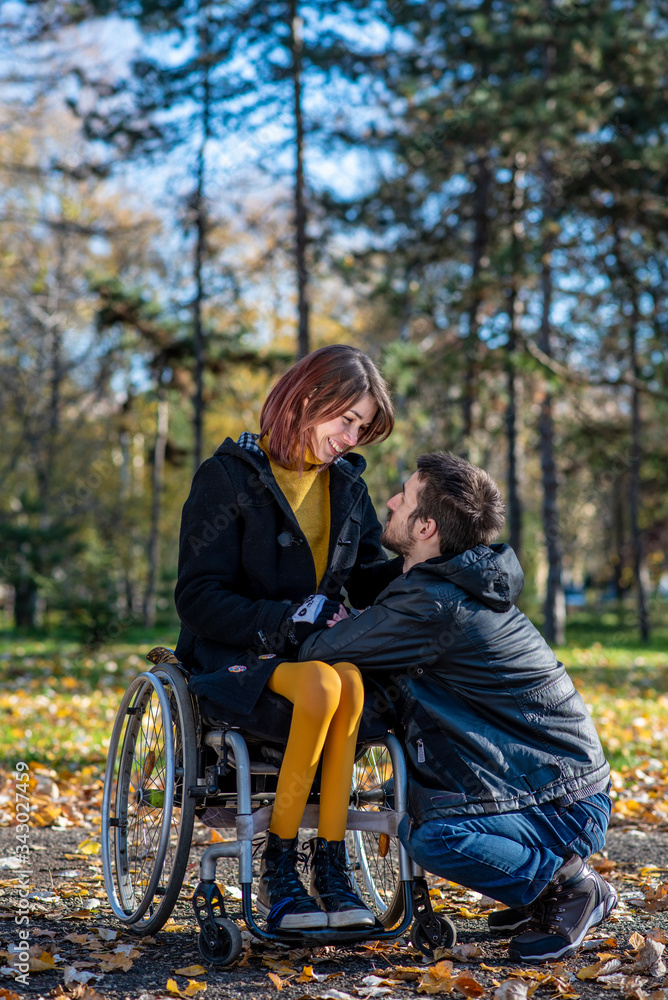 Young disabled woman in a wheelchair with boyfriend. Man with disabled girl in a wheelchair Young disabled woman in a wheelchair with boyfriend. Man with disabled girl in a wheelchair