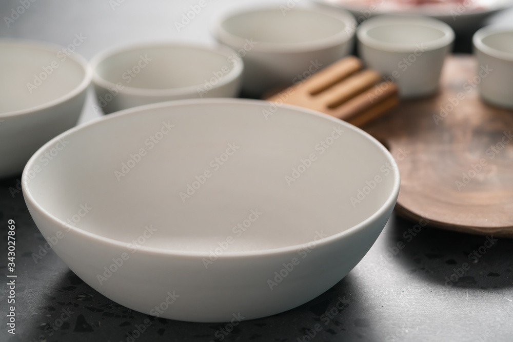 Empty matt white ceramic handmade tableware set on concrete countertop Empty matt white ceramic handmade tableware set on concrete countertop