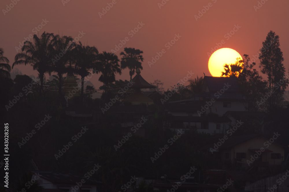 Beautiful Sunrise Behind a Temple and Palms at Laos, seen from Chiang Khong, Thailand, Asia
