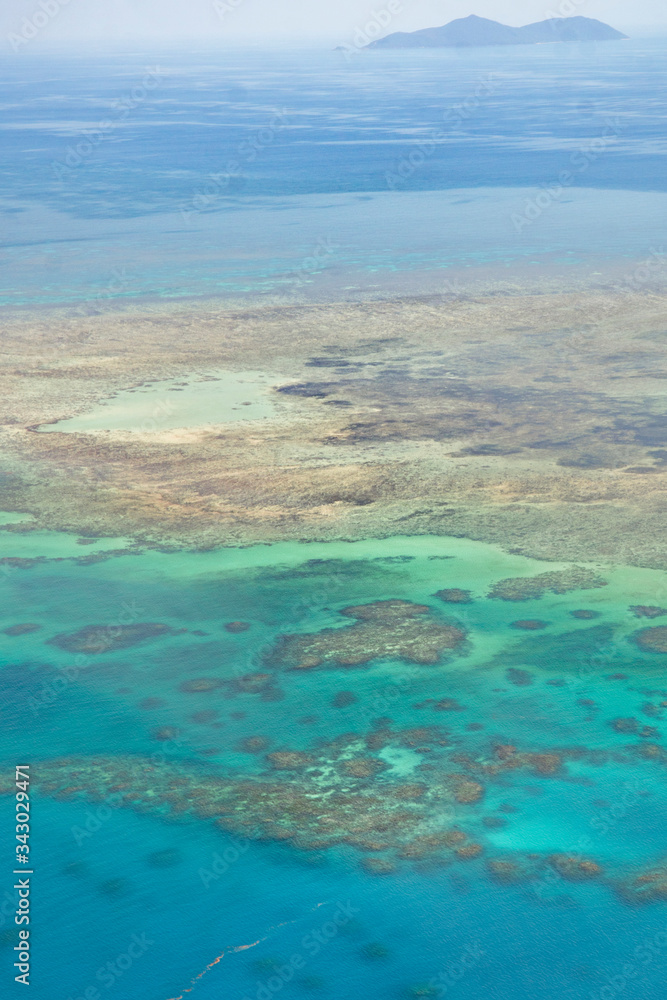 Obraz premium Great Barrier Reef Blue Ocean Sea view. Beautiful aqua & turquoise waters, with coral reef patterns in the ocean. View from helicopter, on vacation. Marine life, global warming, protection, island