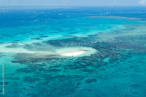 Island in Great Barrier Reef Blue Sea view. Beautiful aqua & turquoise waters, with sand, coral reef patterns in the ocean. View from helicopter, on vacation. Tropical, paradise, holiday concepts © Jam Travels