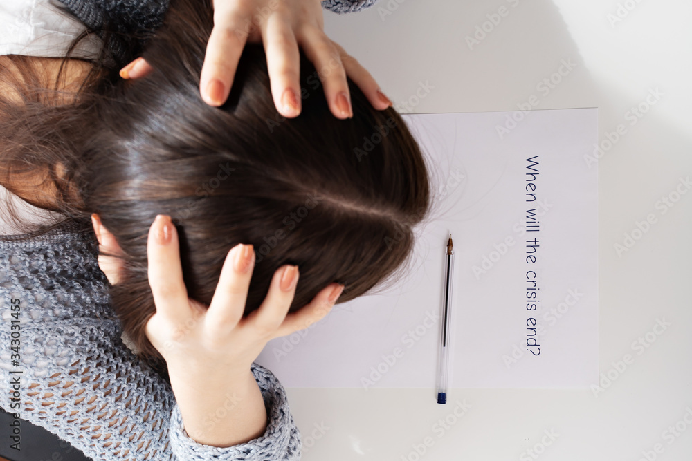 Fototapeta premium Financial collapse and unemployment. Female hands write on a piece of paper when the crisis will end