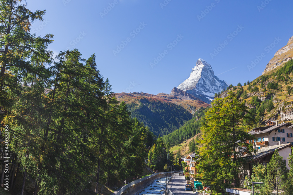 Landscape of Matterhorn mountain peak view from Kirchbrucke bridge with row of green pine tree and Gornera river in Zermatt, Switzerland