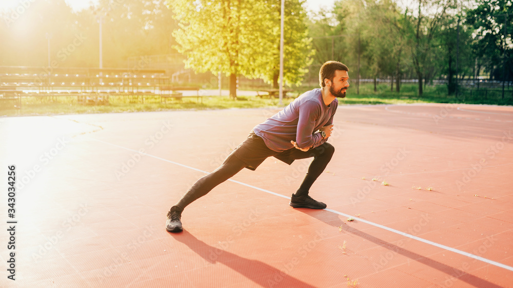 Obraz premium Male doing stretching exercise, preparing for a morning workout in the park