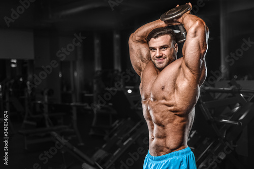 Bodybuilder strong man pumping up triceps muscles