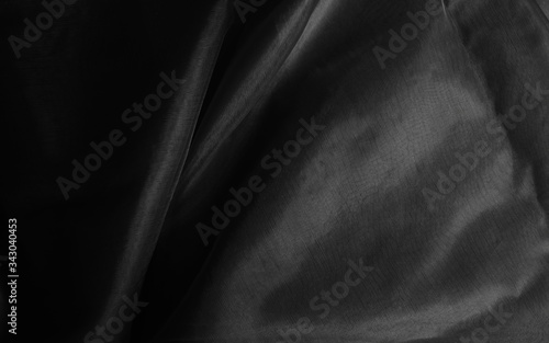 Crumpled charmeuse cloth in monochrome, black background with light and shadow 