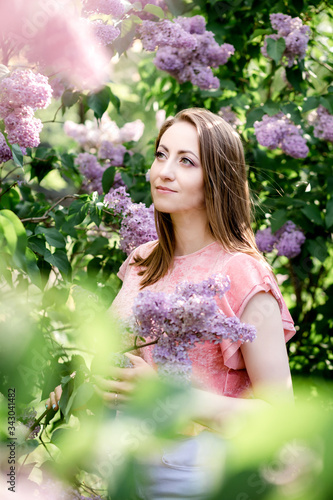 Portrait of woman holding lilac flowers bouquet on blossomig bush background photo