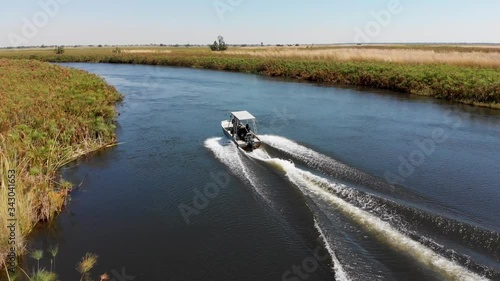 Aerial parallax shot around a fishing boat speeding along a river in the Okovango Delta in Botswana.  photo