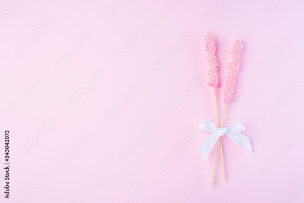 Rock candy on pink paper background decorated with a white bow, horizontal, top view, copy space Rock candy on pink paper background decorated with a white bow, horizontal, top view, copy space
