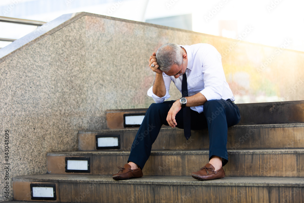 Stressed business man. Tired depressed bored or stressed businessman sitting on the walkway in the city. business failure bankruptcy Stressed business man. Tired depressed bored or stressed businessman sitting on the walkway in the city. business failure bankruptcy