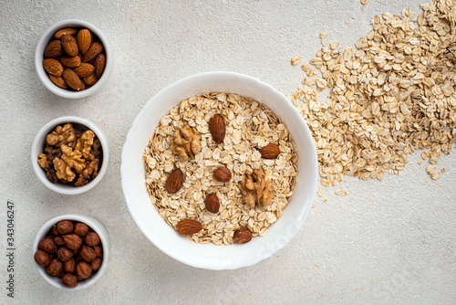 Dry oatmeal with assorted nuts on a white background. Healthy breakfast concept. Top view, copy space.