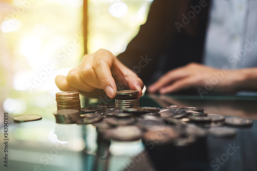 Cuadro en lienzo Businesswoman stacking coins on the table for saving money and financial concept
