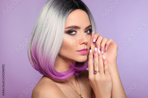Ombre bob short hairstyle. Woman portrait with blond purple hair and manicured nails. Beauty makeup. Beautiful girl model isolated on violet background.