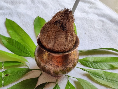 Copper Kalash with coconut and mango leaf with floral decoration on a white background. photo