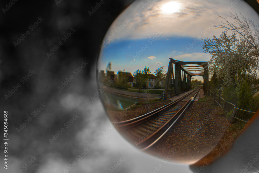 Eine Zugbrücke durch eine Glaskugel fotografiert und der Hintergrund ist in schwarz-weiß dargestellt.