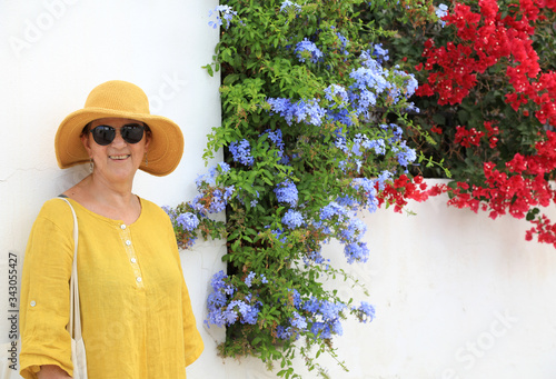 mujer madura con sombrero amarillo y gafas oscuras entre bugambilias turista almería 4M0A6536-as20 photo