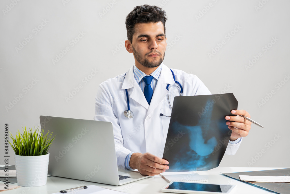 Handsome young doctor looking at x-ray scan Handsome young doctor looking at x-ray scan