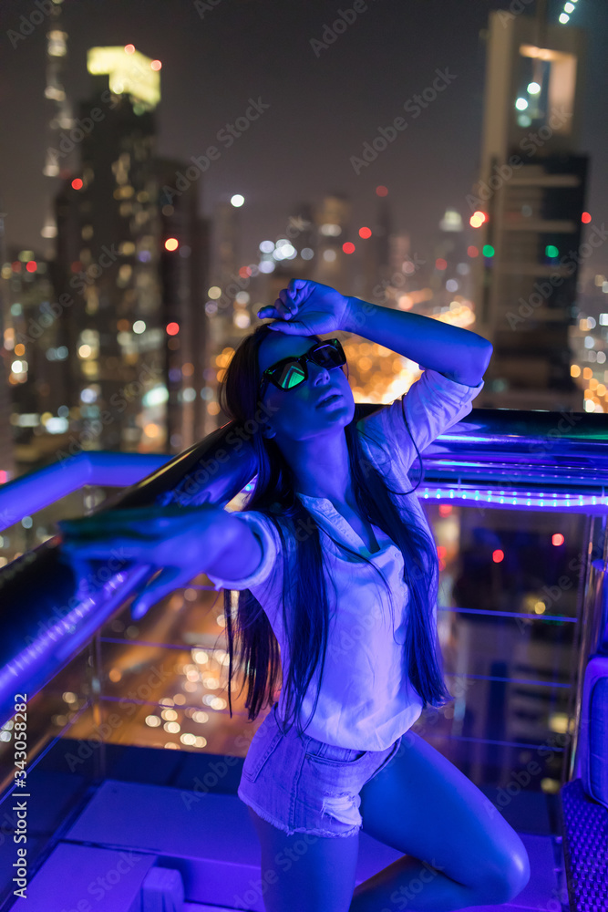 Young woman standing on the view of night light skyscrapers