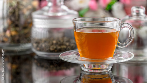 Tea pouring closeup. Tea being poured into glass transparent tea cup. Tea time concept. Transparent glass teapot and teacup. Herbal tea, green tea, tea with Jasmine. Put the sugar in a Cup and stir.