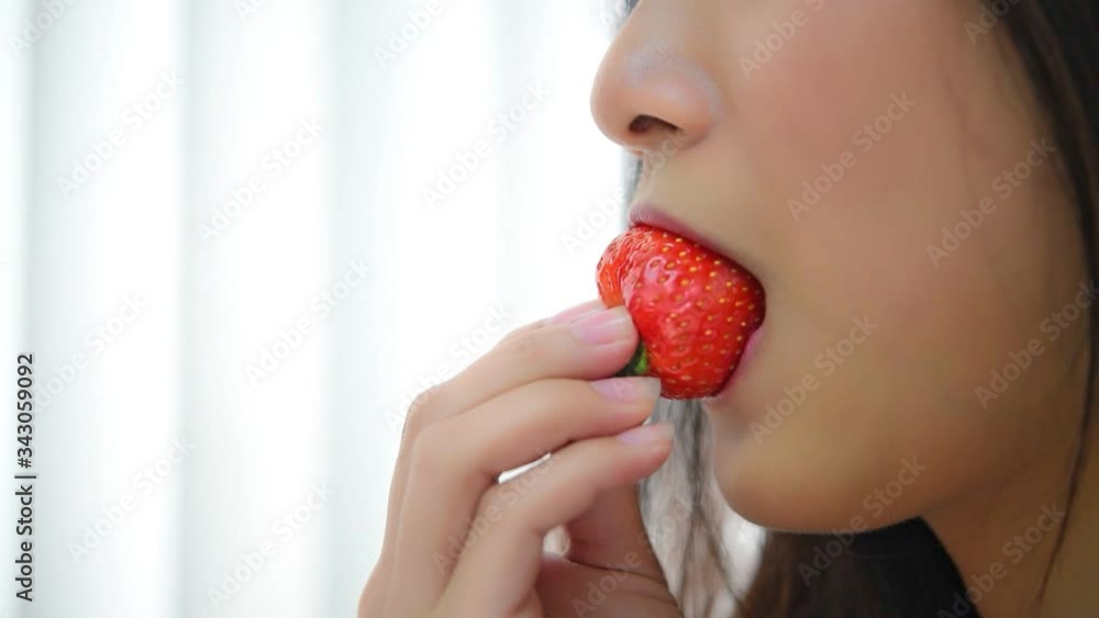 Asian pretty woman holding and eating fresh strawberry is red berry fruit color and sweet juicy with enjoy and happy emotion in concept food, healthy eating in life (Slow motion) Asian pretty woman holding and eating fresh strawberry is red berry fruit color and sweet juicy with enjoy and happy emotion in concept food, healthy eating in life (Slow motion)