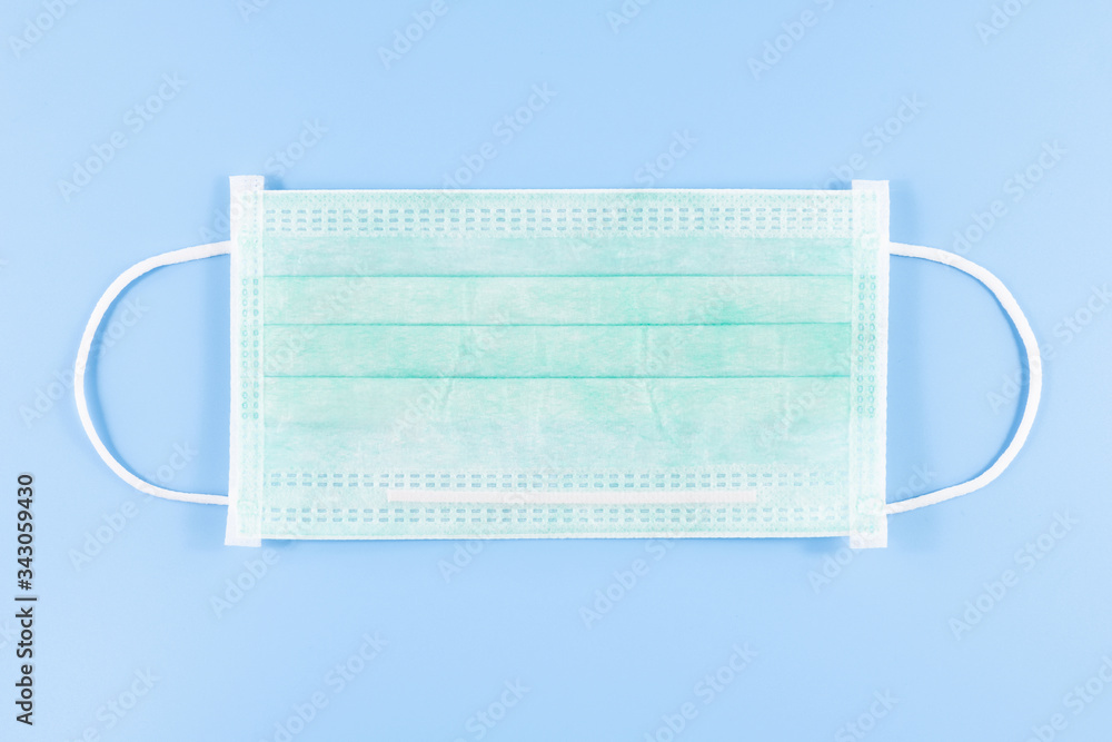 Medical surgical face mask for coronavirus disease (COVID-19) prevention on blue background Medical surgical face mask for coronavirus disease (COVID-19) prevention on blue background